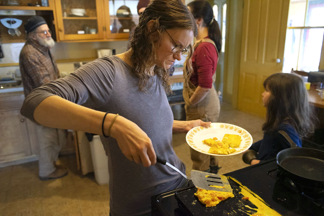 A woman plates eggs from a skillet.